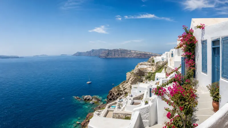 White island houses with pink flowers above a deep blue sea