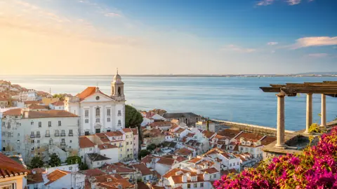 Terracotta rooftops above the sea, with pink bougainvillea