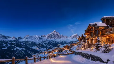 Snowy chalets under alpine peaks at dusk